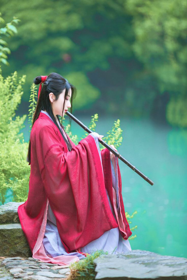 Model with red hanfu playing flute